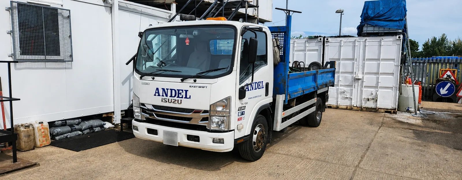 Isuzu dropside tipper parked in a plant yard